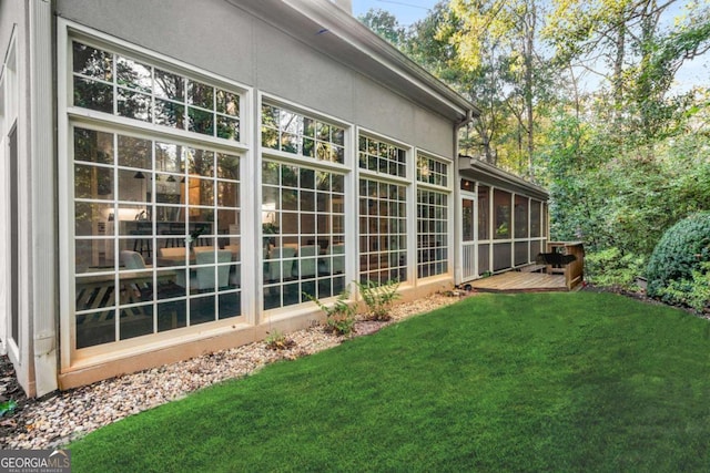 exterior space with a sunroom, a lawn, and a wooden deck