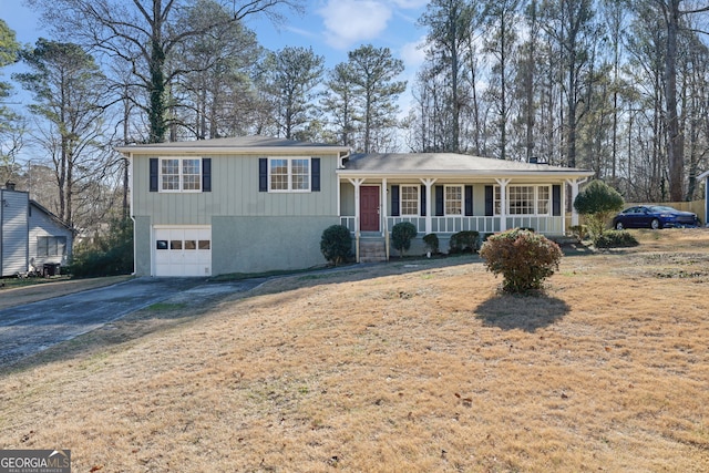 split level home with a porch, a garage, and a front lawn