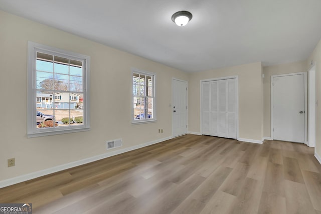 unfurnished bedroom with multiple windows and light hardwood / wood-style flooring