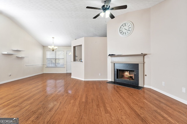 unfurnished living room featuring ceiling fan with notable chandelier, a textured ceiling, hardwood / wood-style flooring, and lofted ceiling