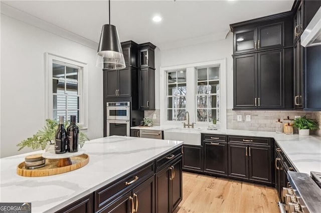 kitchen with decorative backsplash, appliances with stainless steel finishes, crown molding, sink, and pendant lighting