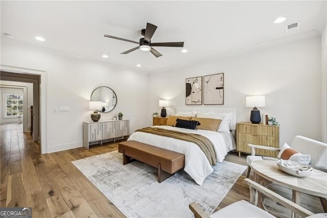 bedroom featuring light hardwood / wood-style floors, ceiling fan, and crown molding