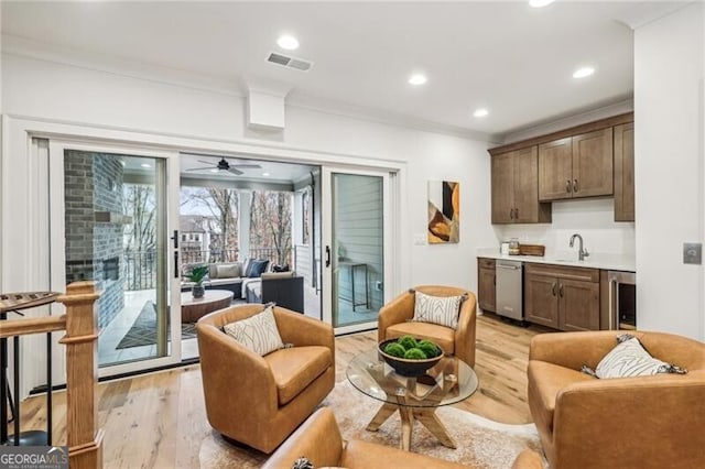 living room featuring light hardwood / wood-style floors, wine cooler, ceiling fan, and crown molding