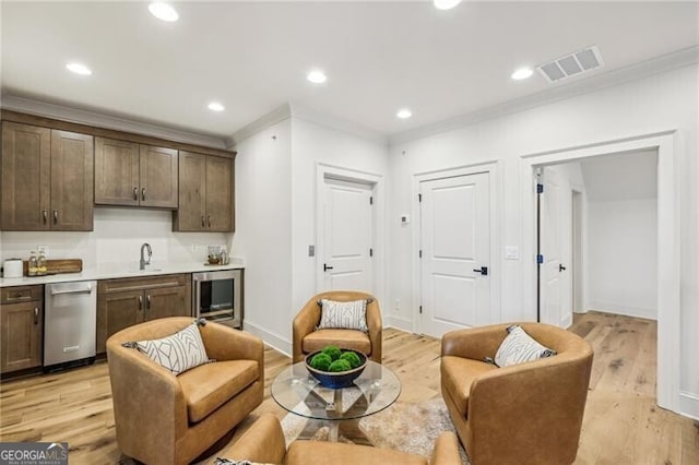 interior space featuring stainless steel dishwasher, light hardwood / wood-style floors, crown molding, and wine cooler