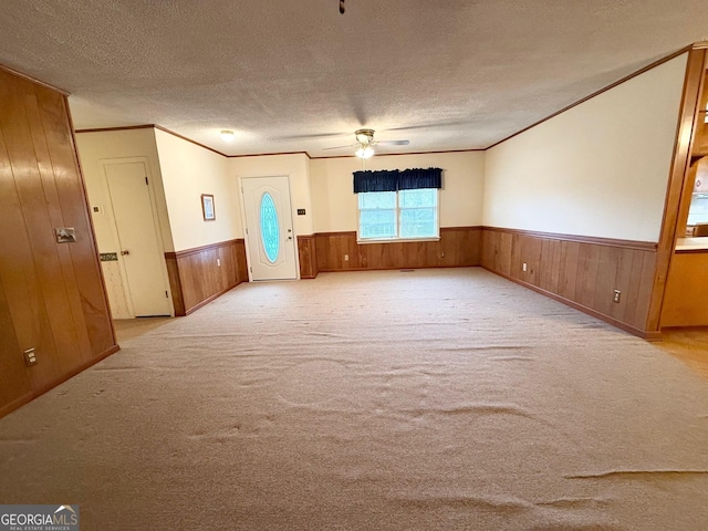 carpeted empty room featuring a textured ceiling, ceiling fan, and crown molding