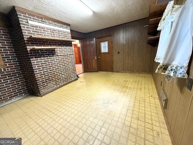 interior space featuring wood walls, brick wall, and a textured ceiling