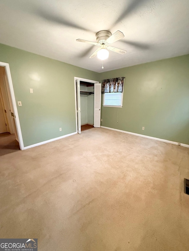 unfurnished bedroom featuring carpet, a closet, and ceiling fan