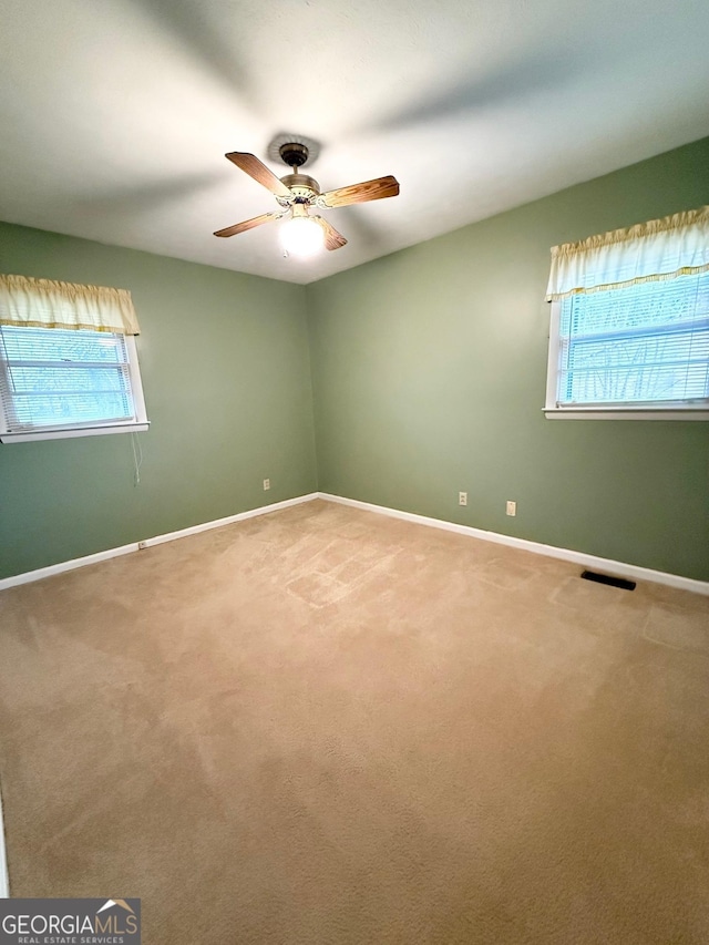 carpeted spare room featuring ceiling fan