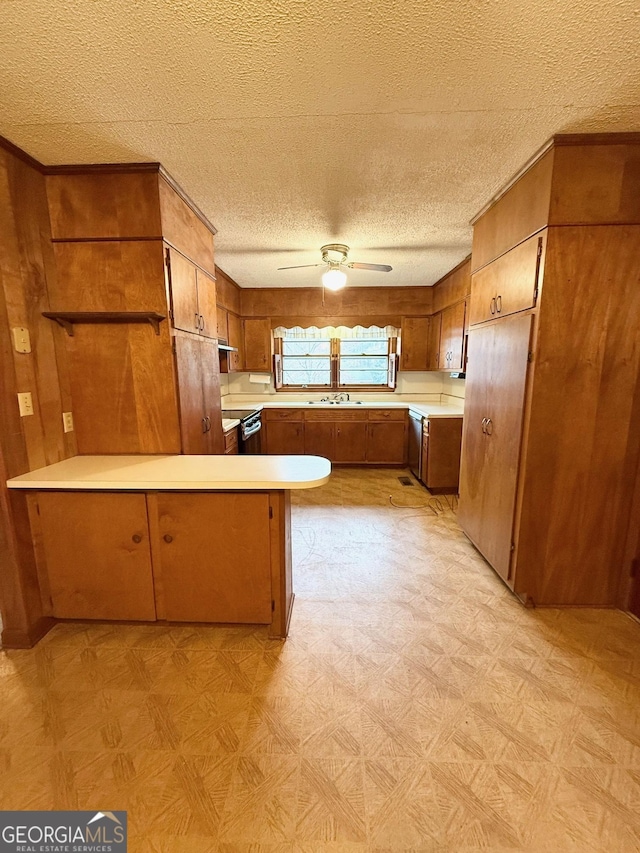 kitchen featuring sink, wooden walls, ceiling fan, a textured ceiling, and kitchen peninsula