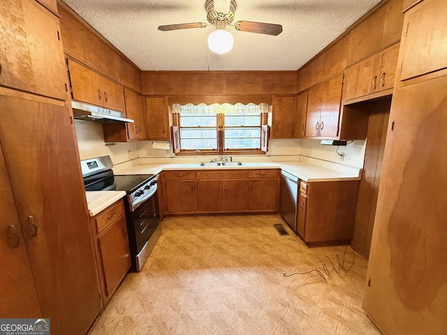 kitchen with wood walls, sink, ceiling fan, a textured ceiling, and appliances with stainless steel finishes