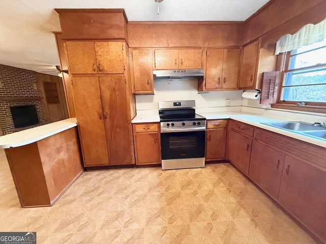 kitchen with a brick fireplace, ceiling fan, a textured ceiling, stainless steel range, and kitchen peninsula