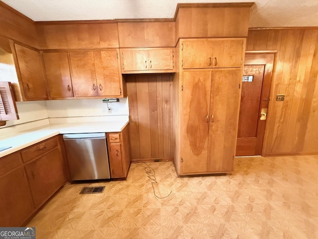 kitchen with dishwasher, wood walls, and a textured ceiling