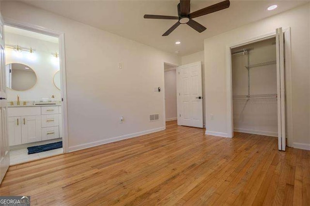 unfurnished bedroom with ceiling fan, sink, light hardwood / wood-style flooring, and a closet