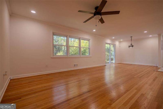 spare room with ceiling fan with notable chandelier, ornamental molding, and light hardwood / wood-style flooring