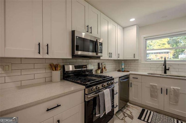 kitchen with decorative backsplash, white cabinetry, sink, and appliances with stainless steel finishes