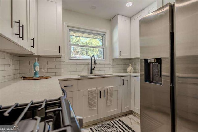 kitchen featuring white cabinets, stainless steel refrigerator with ice dispenser, stove, and sink