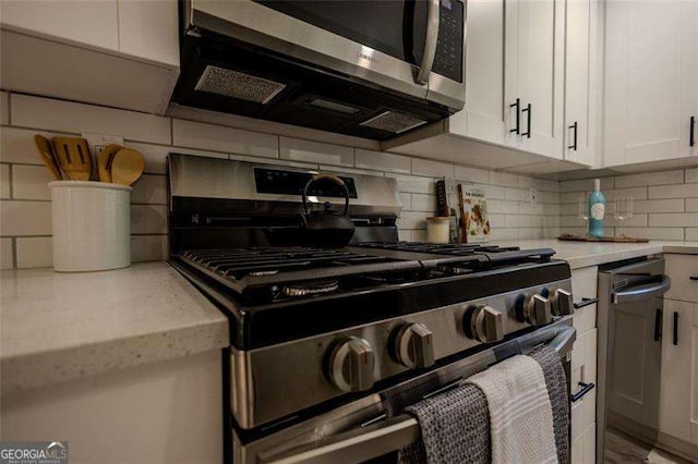 kitchen with decorative backsplash, light stone countertops, white cabinetry, and stainless steel appliances