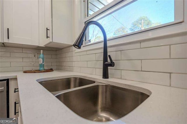 room details featuring decorative backsplash, white cabinetry, light stone countertops, and sink