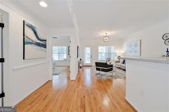 interior space featuring ornamental molding, a notable chandelier, and light wood-type flooring