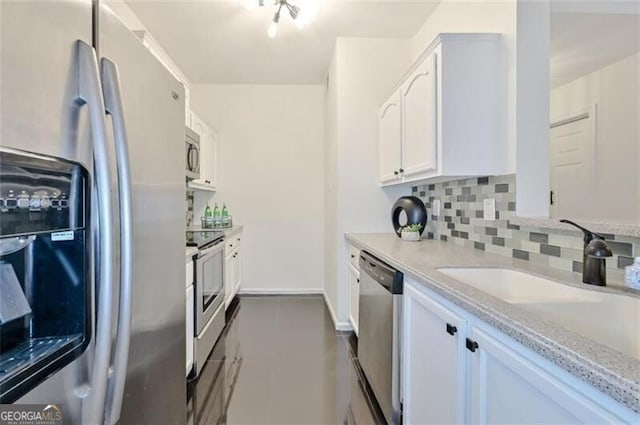 kitchen featuring decorative backsplash, light stone countertops, stainless steel appliances, dark tile patterned floors, and white cabinets