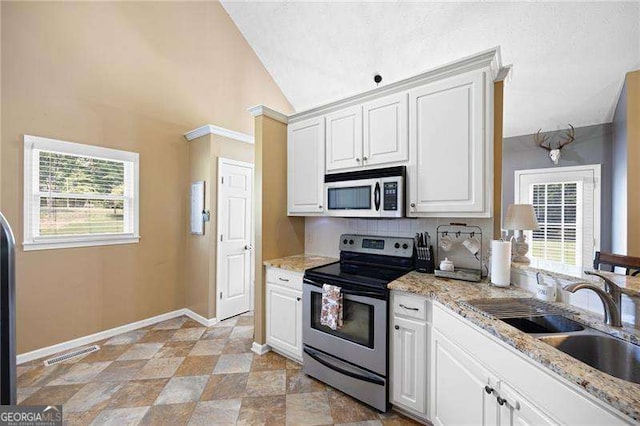 kitchen featuring lofted ceiling, sink, light stone countertops, stainless steel electric range oven, and white cabinetry