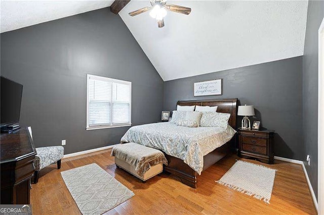 bedroom featuring ceiling fan, light hardwood / wood-style flooring, and lofted ceiling with beams