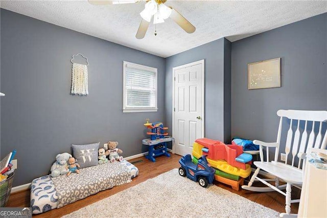 game room featuring hardwood / wood-style flooring, ceiling fan, and a textured ceiling