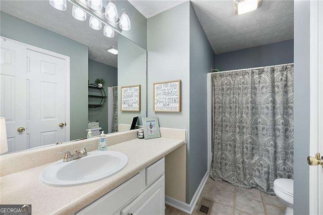 bathroom with tile patterned floors, vanity, toilet, and a textured ceiling