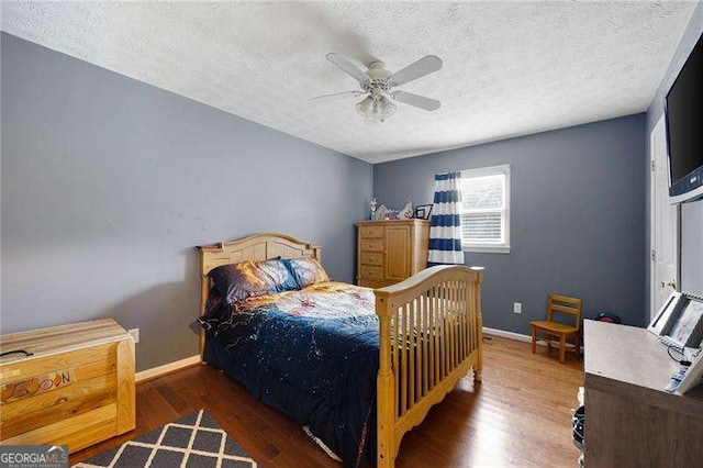 bedroom with a textured ceiling, ceiling fan, and dark wood-type flooring