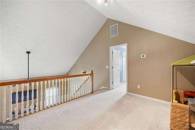 additional living space featuring a textured ceiling, carpet floors, and lofted ceiling