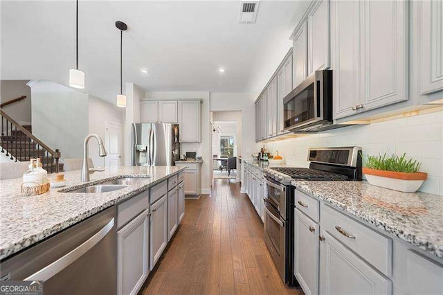 kitchen featuring sink, dark wood-type flooring, appliances with stainless steel finishes, gray cabinetry, and hanging light fixtures