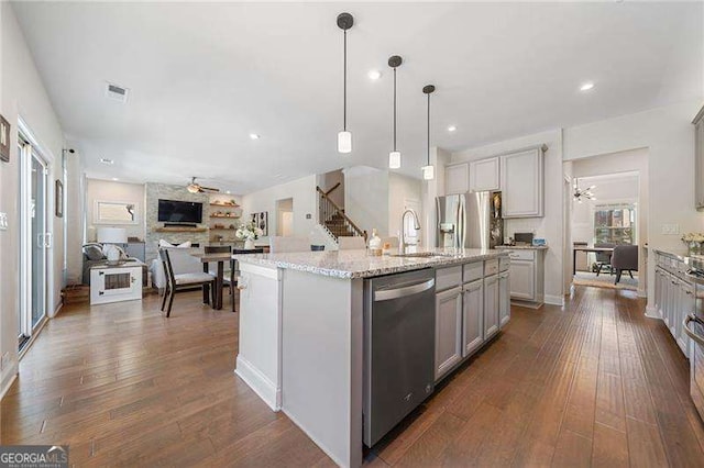 kitchen featuring sink, appliances with stainless steel finishes, gray cabinetry, hanging light fixtures, and an island with sink