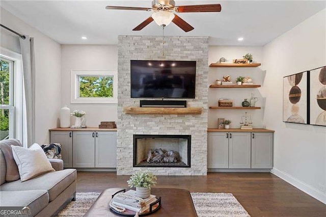 living room featuring dark wood-type flooring, a fireplace, and ceiling fan