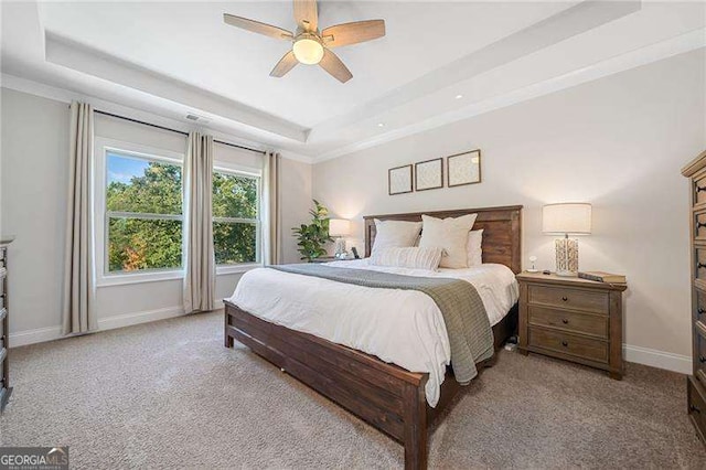 bedroom featuring light colored carpet, ceiling fan, and a tray ceiling