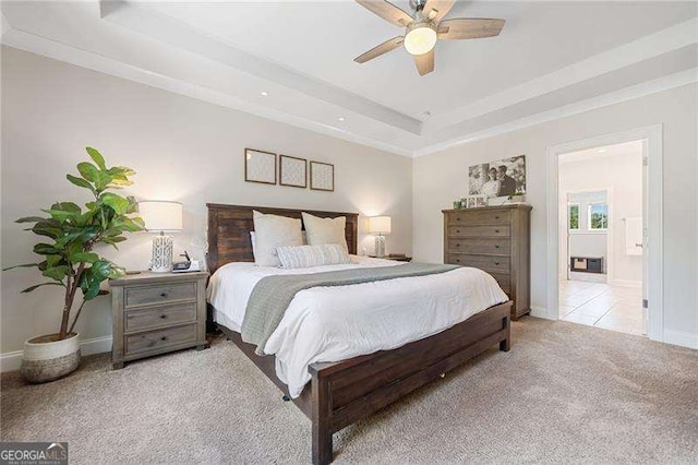 carpeted bedroom with a tray ceiling, ceiling fan, and ensuite bathroom