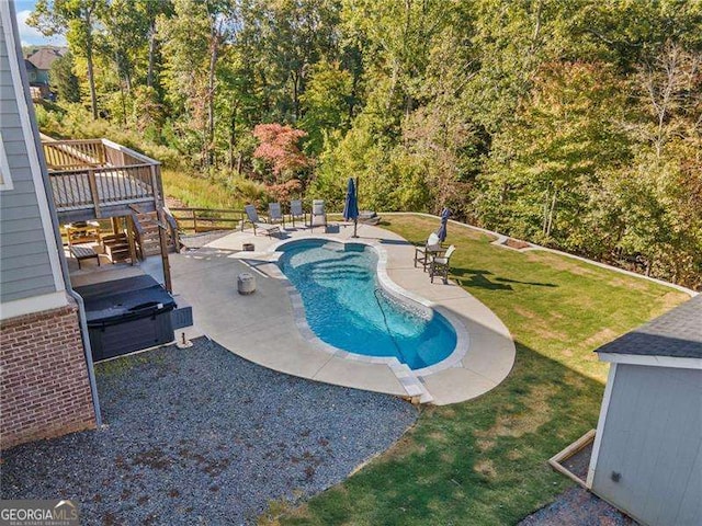 view of pool featuring a wooden deck, a lawn, and a patio area