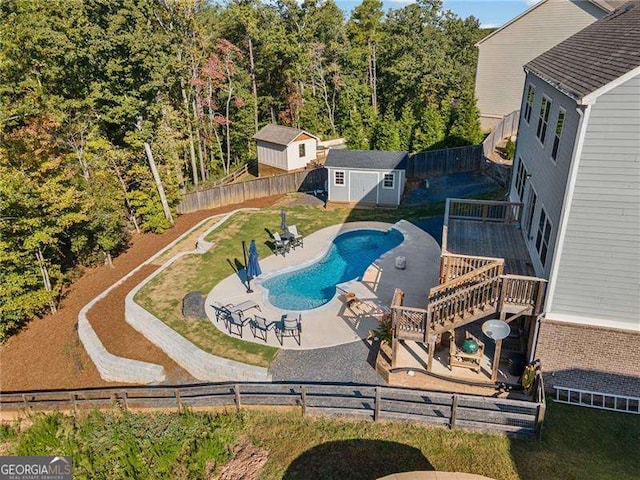 view of pool featuring a deck, a lawn, a patio, and a storage unit