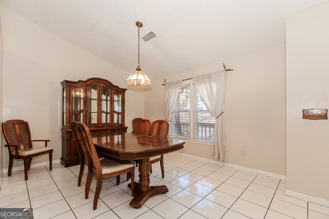 tiled dining room featuring vaulted ceiling and an inviting chandelier