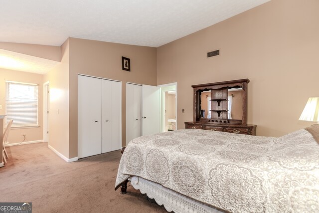 carpeted bedroom with high vaulted ceiling and multiple closets