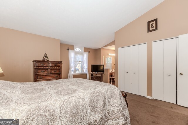 bedroom featuring carpet flooring, lofted ceiling, and two closets