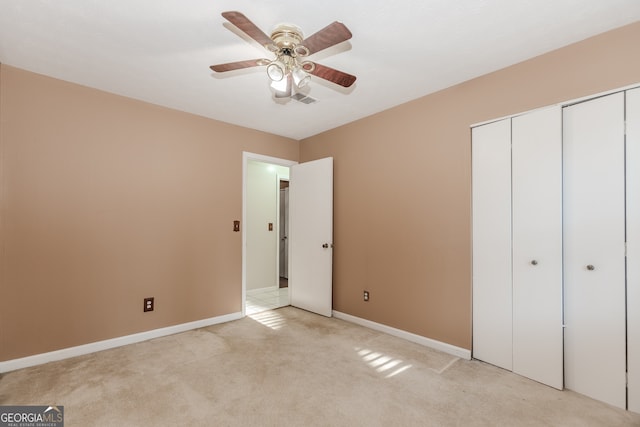 unfurnished bedroom featuring ceiling fan, light colored carpet, and a closet