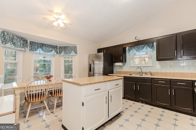 kitchen featuring ceiling fan, sink, stainless steel fridge, lofted ceiling, and decorative backsplash