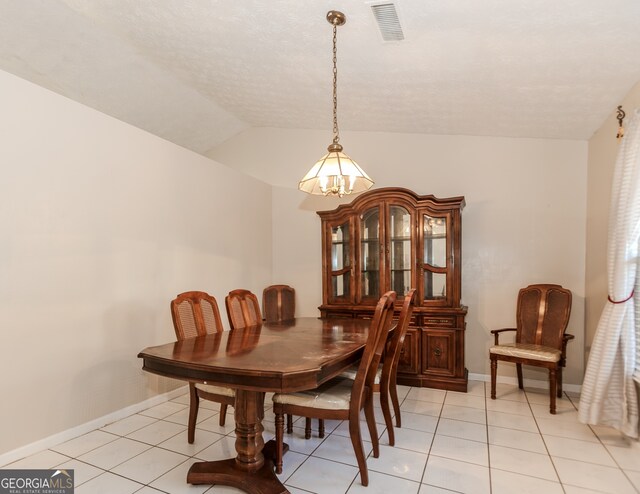 dining area featuring light tile patterned flooring and vaulted ceiling