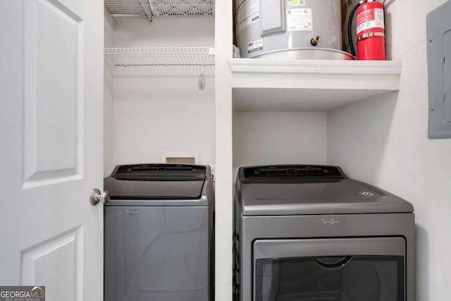 laundry room featuring electric panel, washer and clothes dryer, and water heater