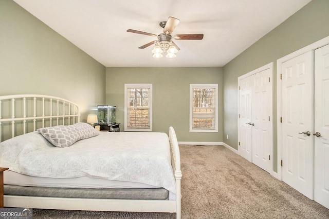 carpeted bedroom featuring ceiling fan and multiple closets