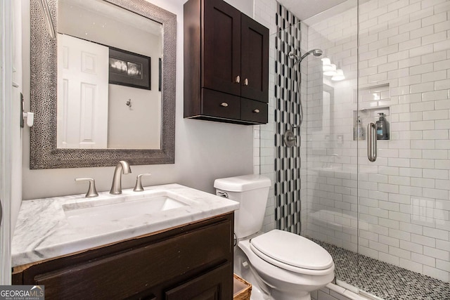 bathroom featuring toilet, vanity, and a shower with shower door