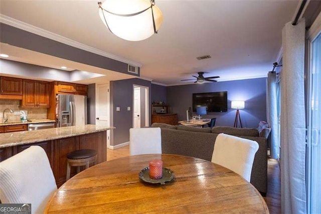 dining space featuring ornamental molding, sink, and ceiling fan