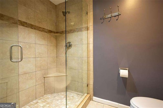 bathroom with toilet, tile patterned floors, and a shower with shower door