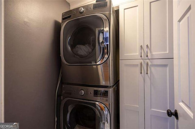 washroom featuring cabinets and stacked washer and clothes dryer