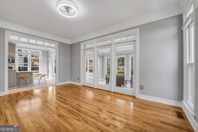 interior space with ornamental molding, a healthy amount of sunlight, and wood-type flooring